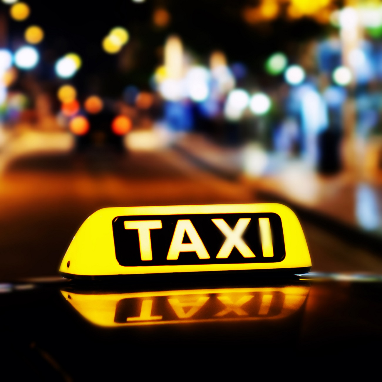 Taxi roof sign, lit up, in front of a blurry city street background